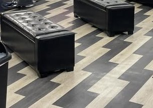 Tufted black benches on a herringbone floor inside LEVEL UP Barbershop